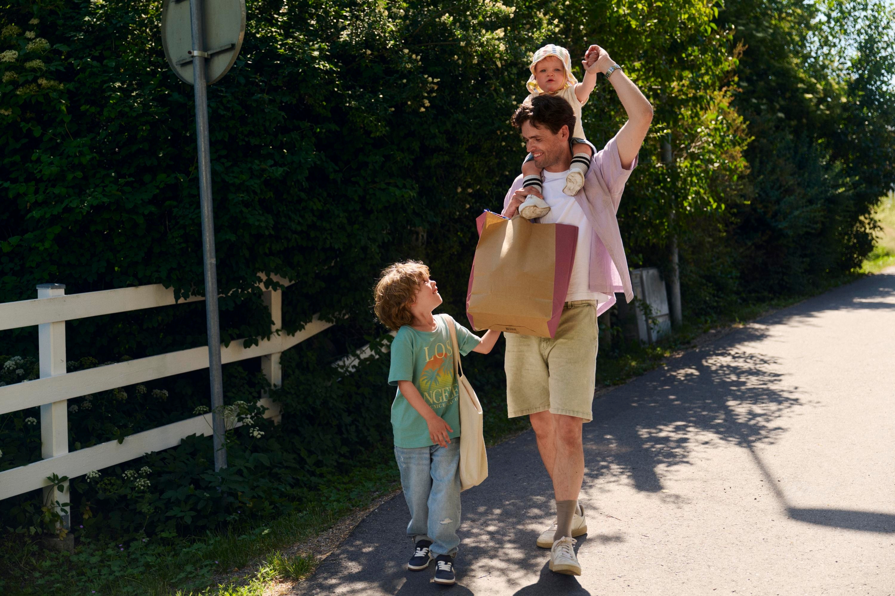 En man och två små barn håller matvarupåsar